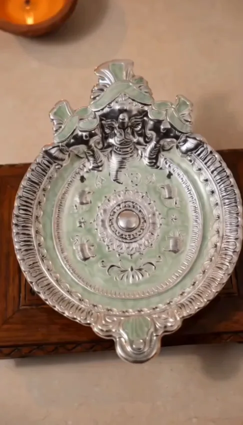 Close-up of an ornate silver plate on a wooden stand